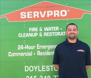 male employee standing in front of green truck