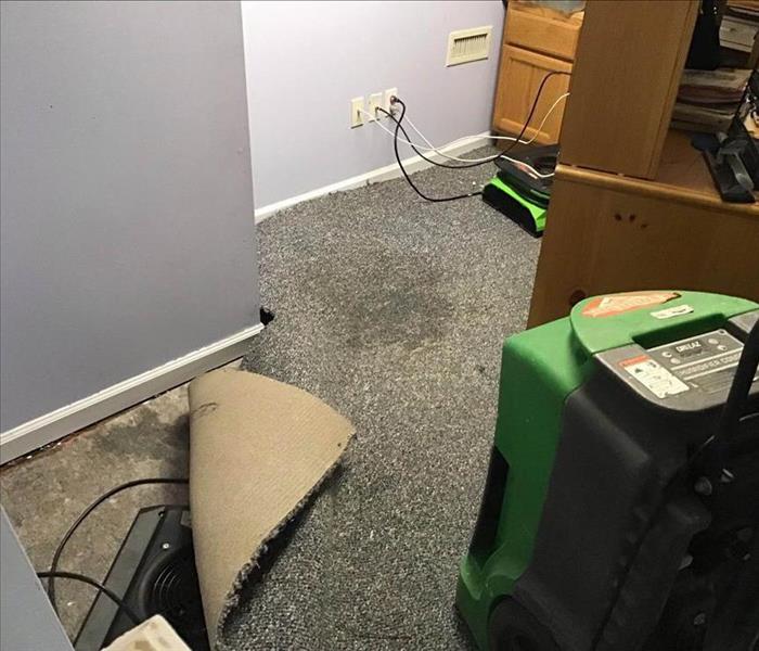 Carpet damaged by water with air movers drying the area