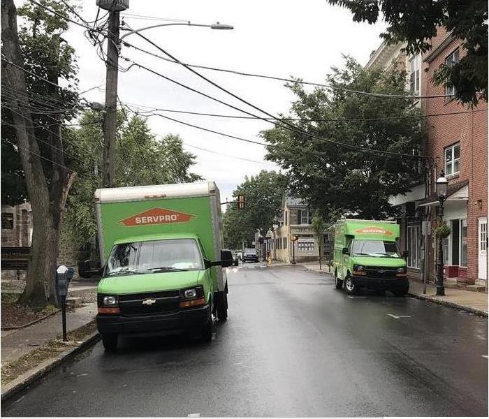 Two SERVPRO trucks parked on a sidewalk.