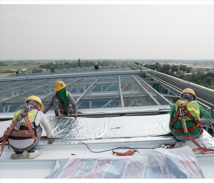 Construction worker wearing safety harness and safety line working on a metal industry roof